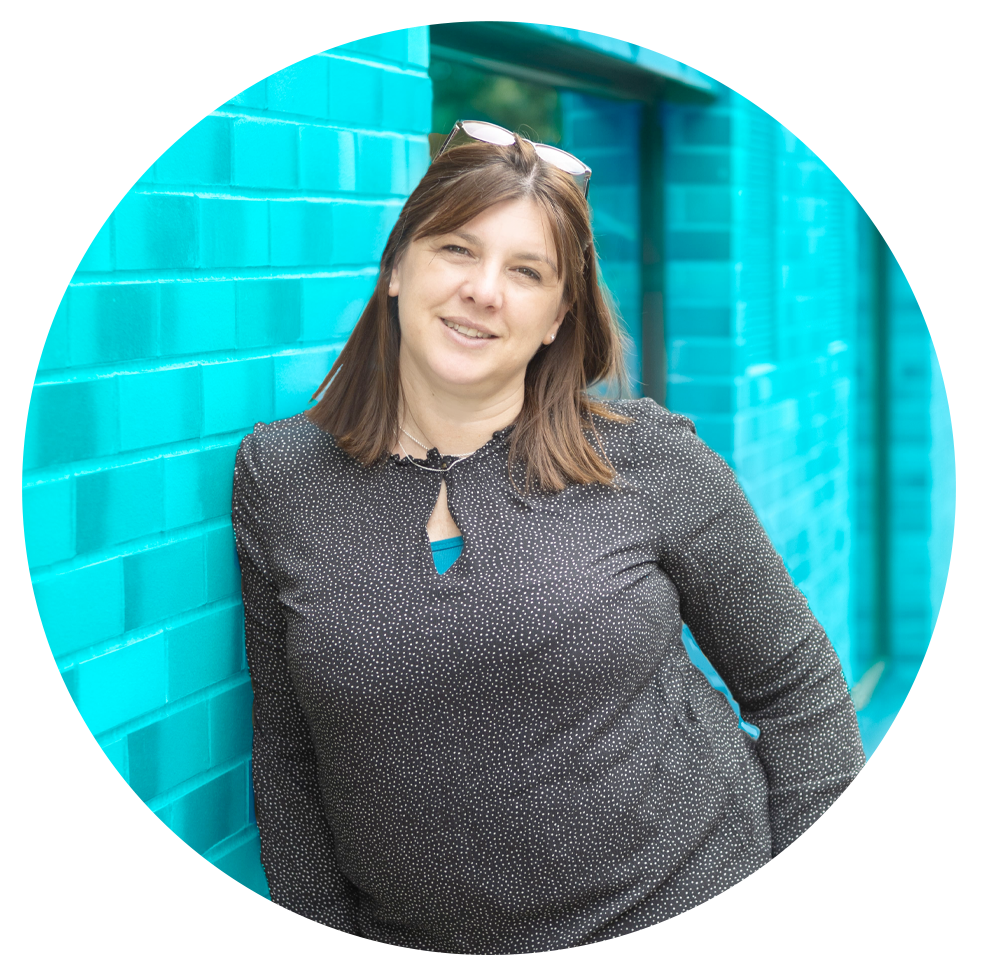 Tania Martin, founder of PegSquared, beside a teal brick wall